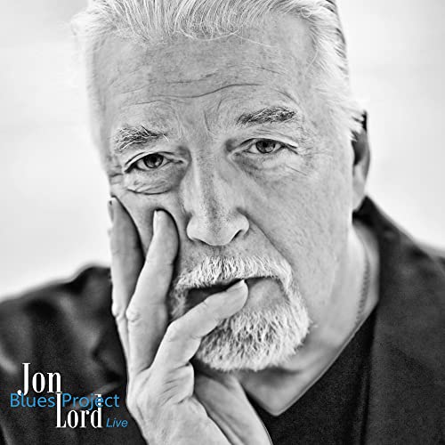 Black and white portrait of Jon Lord, musician, with beard and hand to face.