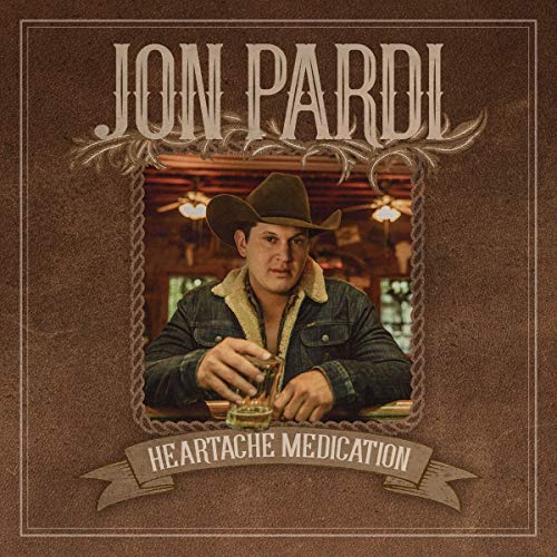 Jon Pardi wearing a cowboy hat and denim jacket, holding a glass at a bar.