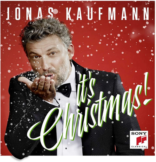 Man in tuxedo blowing snow against red background with "It's Christmas!" text overlay.