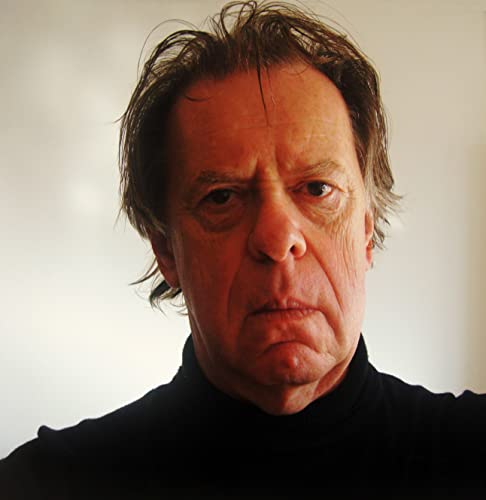 Close-up portrait of a man with short, greying hair and a stern expression.