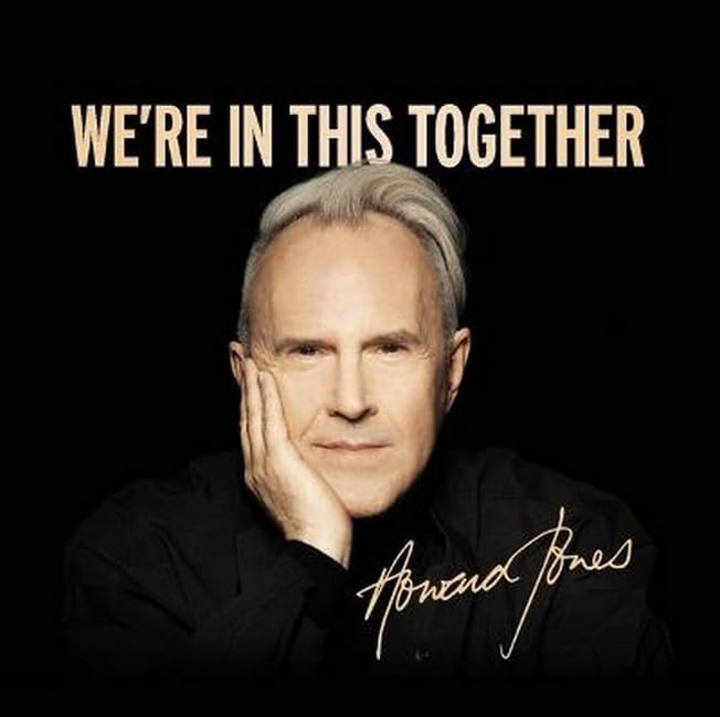 Howard Jones with his hand on his cheek against a black background.
