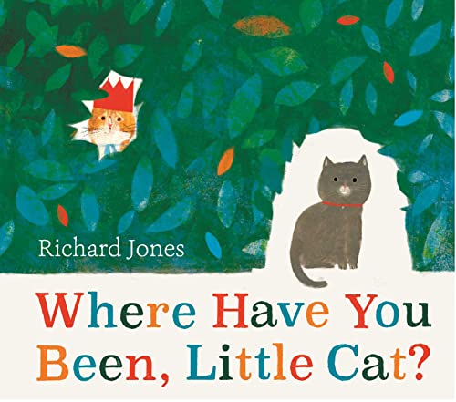 A grey cat sits in a hedge opening, while a ginger cat peeks out.