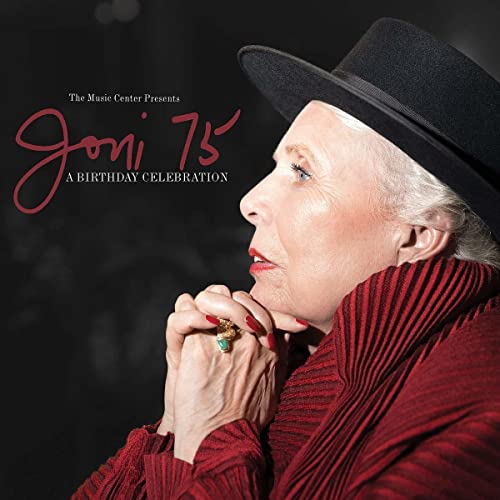 Joni Mitchell in a black hat and red turtleneck, profile view.