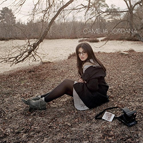 Camelia Jordana album cover: woman sitting outdoors with a vintage camera.