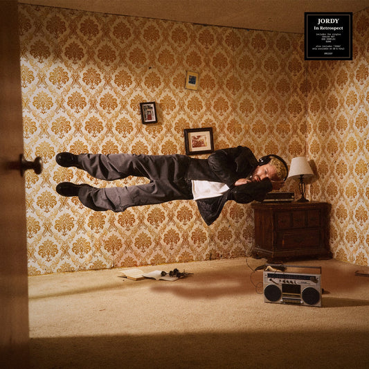 Album cover: man in suit levitates in a patterned room with a boombox.