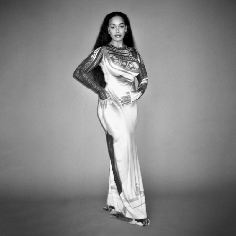 Black and white portrait of Jorja Smith in a long, patterned dress.