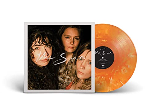 Vinyl record with orange and cloudy clear swirl, album cover with three people.