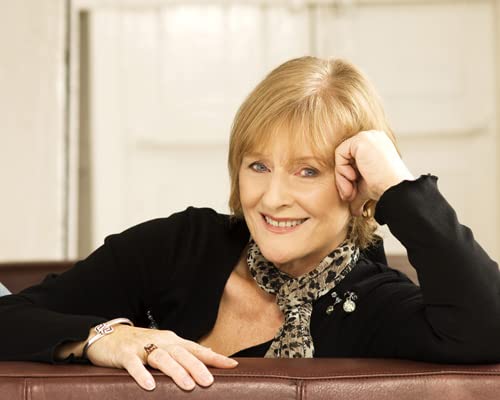 Older woman with short blonde hair smiling, resting chin on hand.