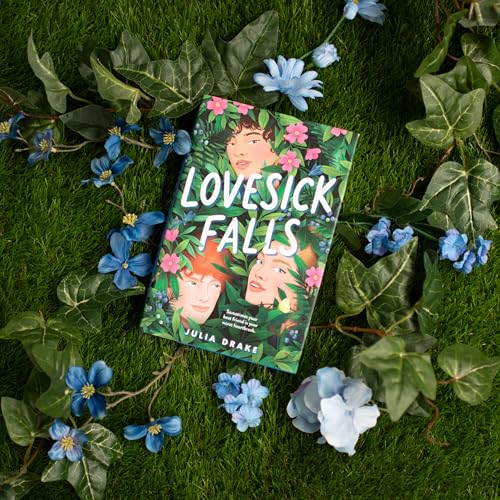 Book cover for “Lovesick Falls” surrounded by artificial greenery and blue flowers.