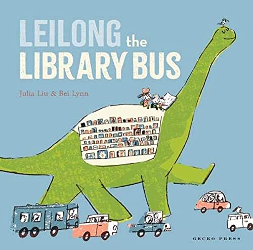 Green dinosaur-shaped bus filled with books, with smaller vehicles nearby.