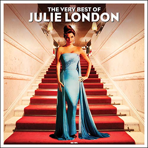 Julie London in a blue gown standing on a red carpeted staircase.