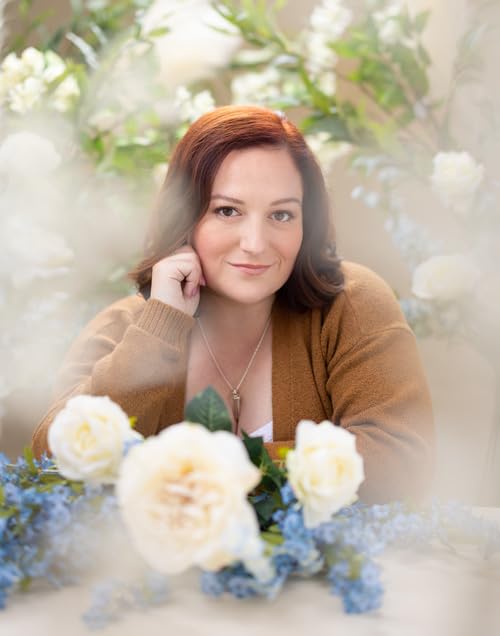 Woman with red hair poses with white roses and blue forget-me-nots.