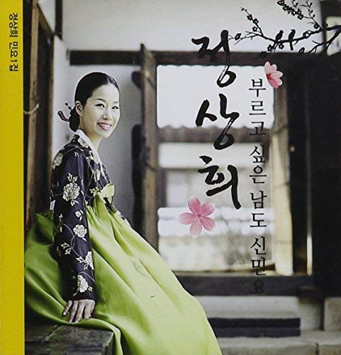 A woman in a traditional Korean hanbok sits in front of a blurred building.