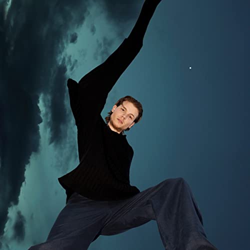 Person in black clothing reaching upwards against a dark blue sky.
