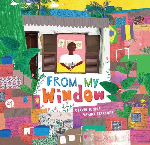 A person writes at a window overlooking a colorful, dense neighborhood of brick houses.