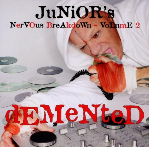 Man in white robe surrounded by CDs, holding phone and DJ controller.