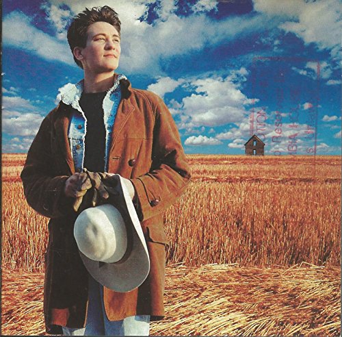K.d. Lang album cover: woman in a brown coat, wheat field, blue sky.