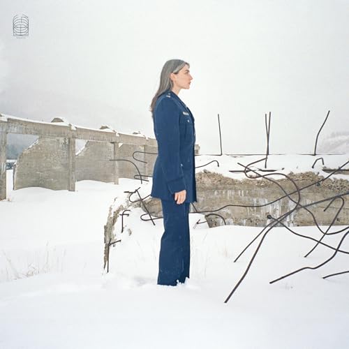 Woman in blue suit standing in a snowy, desolate landscape.