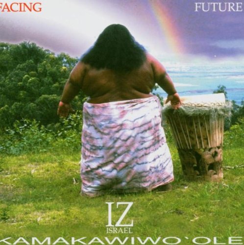 Israel Kamakawiwoʻole facing away, standing in a field with a drum.