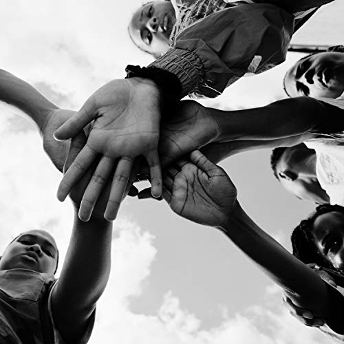 Black and white photo of a group hand stack, looking upwards.