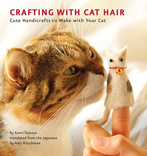 Tabby cat looking at a small, felted cat figure held by a hand.