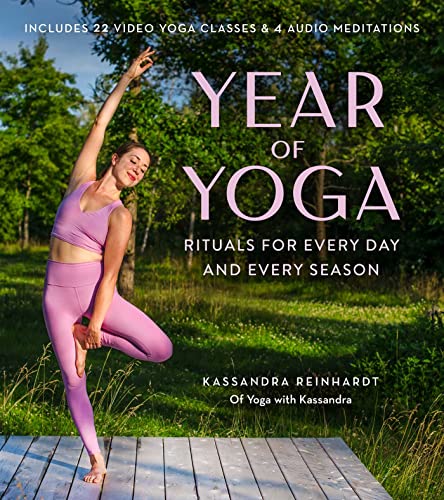 A woman in lavender yoga clothes performs a tree pose on a wooden deck.