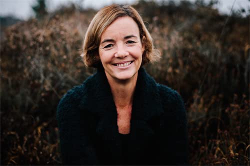 Smiling woman with short brown hair, wearing a dark coat.