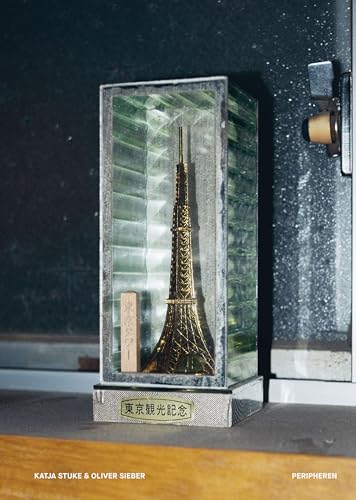Glass case displaying a golden miniature of Tokyo Tower and a wooden block.