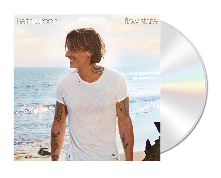 Keith Urban standing on a beach with a CD disc next to the cover.