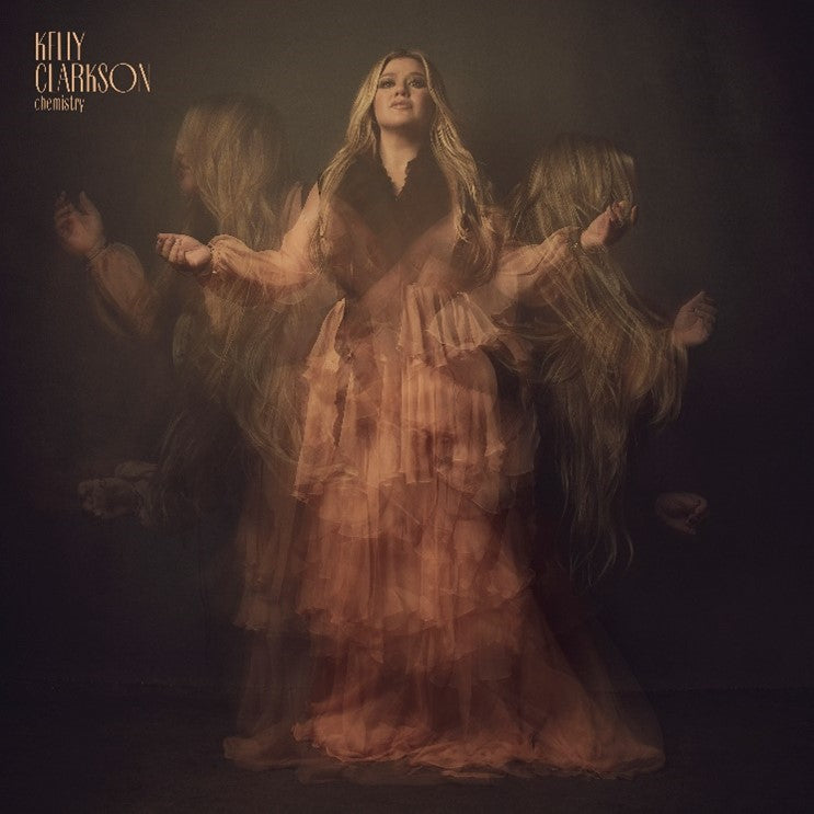 The image depicts a woman in a flowing dress, surrounded by multiple ghostly images of herself. For accessibility purposes, a suitable alt text could be: "Album cover featuring Kelly Clarkson in a layered, ghostly effect."