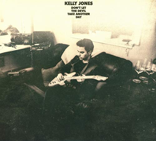 CD cover: Man with guitar in a dimly lit room.