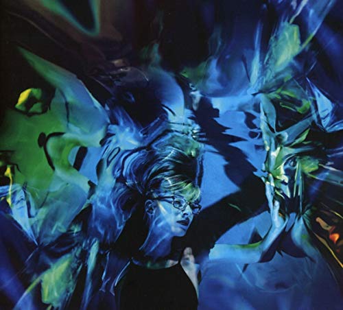 Woman with glasses amidst swirling blue and green abstract light.