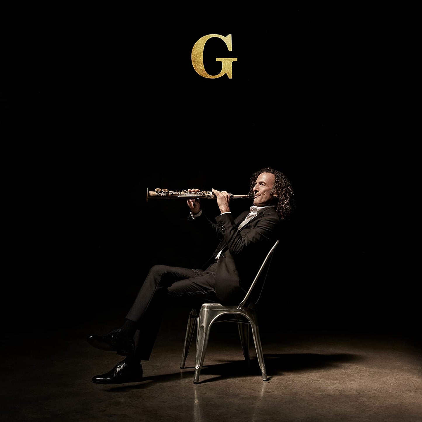 Kenny G playing a saxophone, seated on a chair against a dark background.