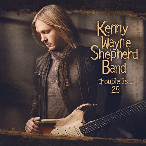 Kenny Wayne Shepherd holding a guitar on the Trouble Is... 25 album cover.