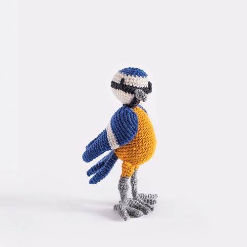 A small, handmade crochet bird with blue, white, and yellow yarn on a white background.