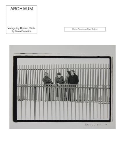 Black and white photograph of four people behind a vertical-slatted fence.