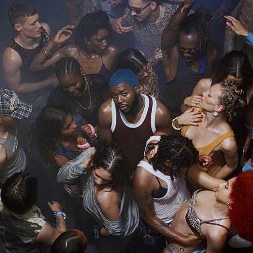 Khalid surrounded by a diverse crowd in a dimly lit, energetic space.