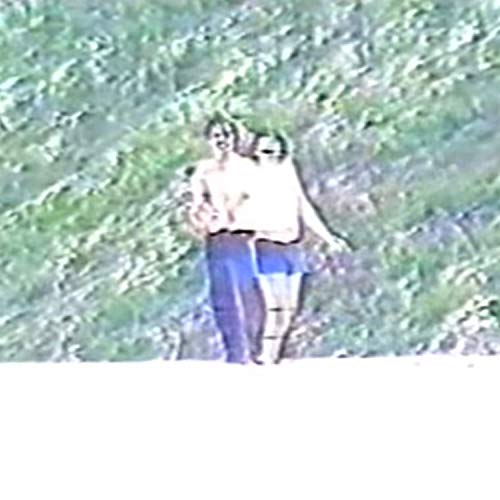 Two figures walking away from the viewer in a blurry landscape.