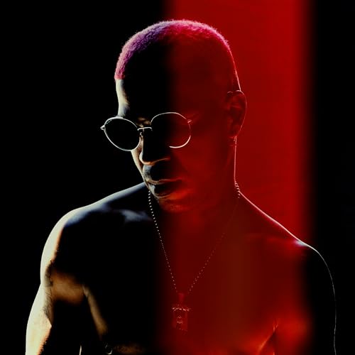 Kid Cudi portrait with pink-tinted hair, wearing sunglasses, in red lighting.