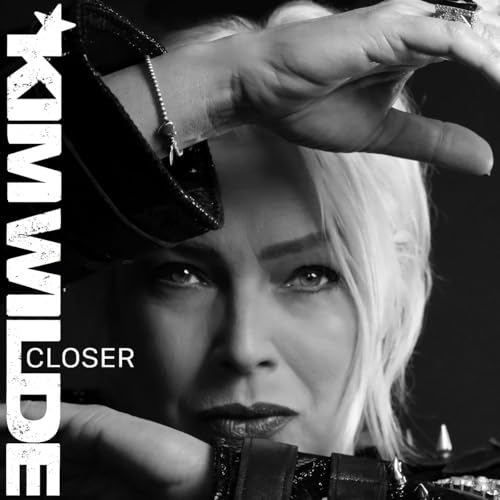 Black and white portrait of Kim Wilde with her hands framing her face.