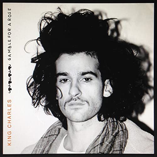 Black and white portrait of a man with curly hair, album cover.