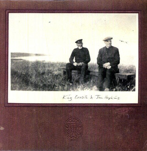 Black and white photo of two men seated on a grassy bank.