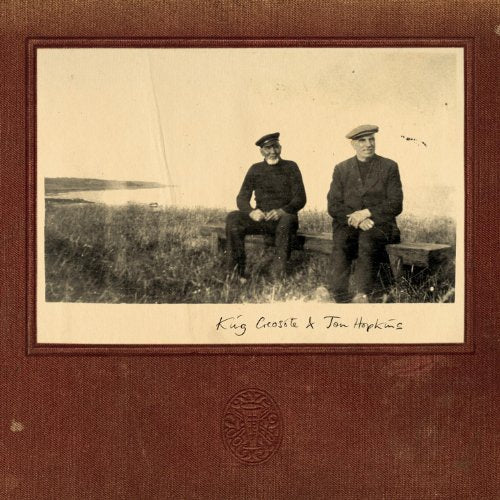 Sepia-toned photo of two men seated on a bench in a field.