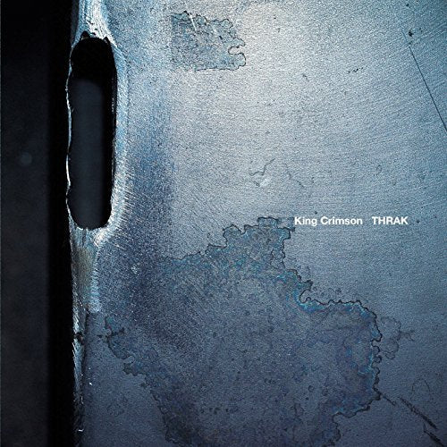 Album cover showing a textured, weathered blue metal surface with a dark vertical slot.