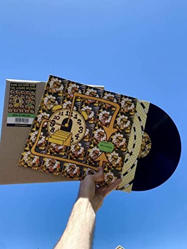 King Gizzard vinyl record with clockwork cover held against a blue sky.