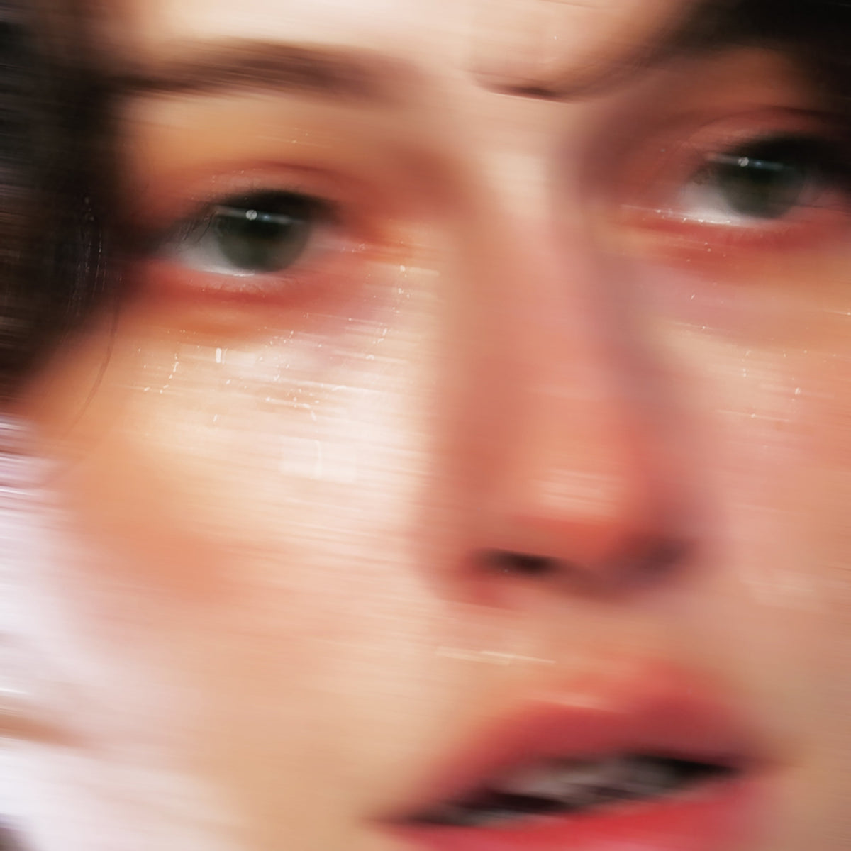Blurred close-up portrait of a person with green eyes, album art.