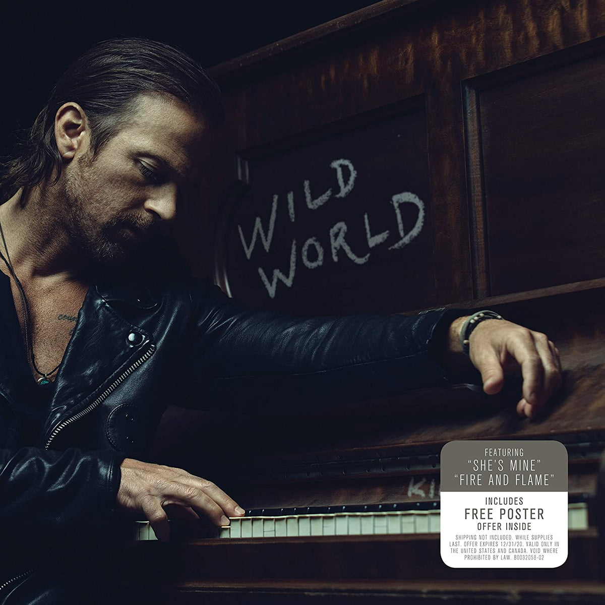 Man playing piano with "Wild World" written on chalkboard behind him, dark background.