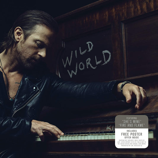 Man playing piano with "Wild World" written on chalkboard behind him, dark background.