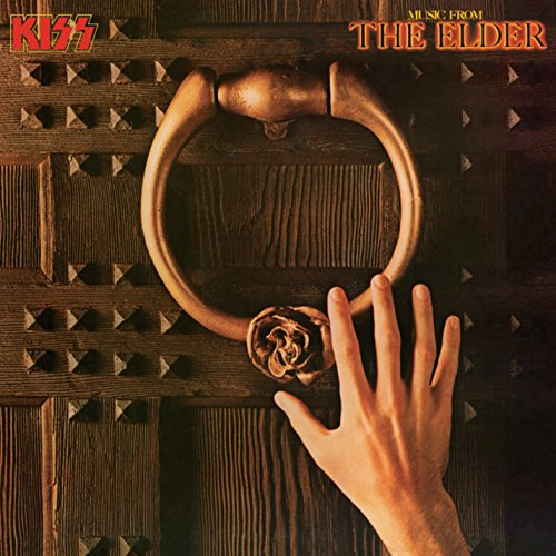 A hand reaches toward a brass door knocker on a dark wooden door.