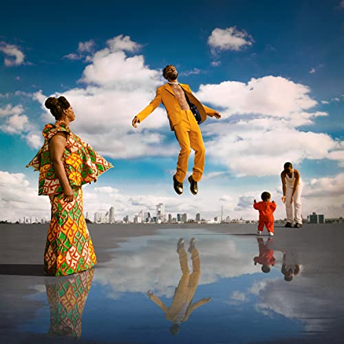 People in vibrant clothing pose against a blue sky and city backdrop.